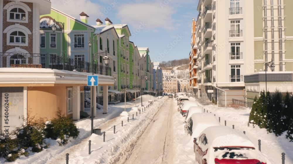 City street massively covered with snow after snowfall. Colored buildings and cars. City street massively covered with snow after snowfall. Colored buildings and cars.