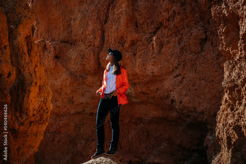 Impressed woman tourist walking in red canyon. Brave female hiker in solo trekking. Adventure, wanderlust, sightseeing.