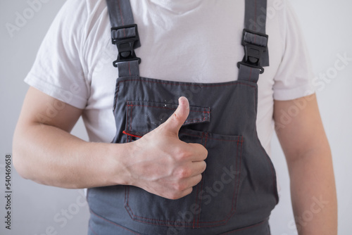 Impersonal worker in overalls showing thumbs up