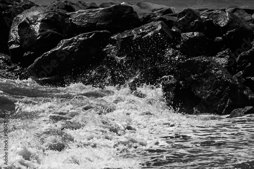 sea waves with foam and large stones. black and white beach photography