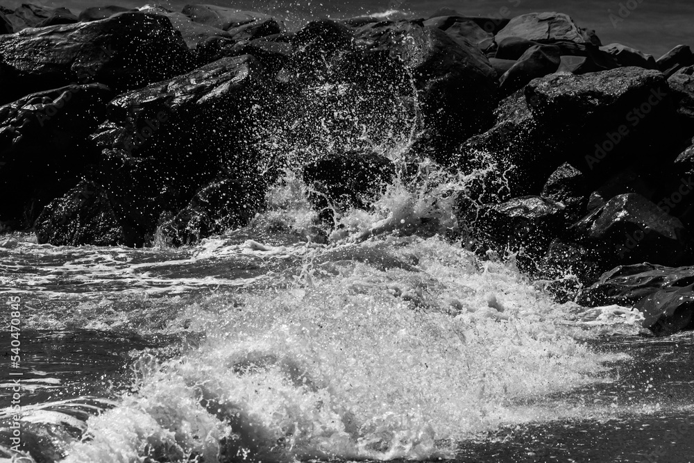 sea waves with foam and large stones. black and white beach photography