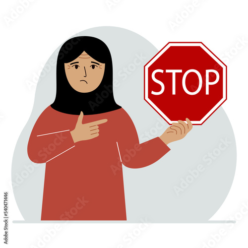 A woman holds a red stop sign in his hand.