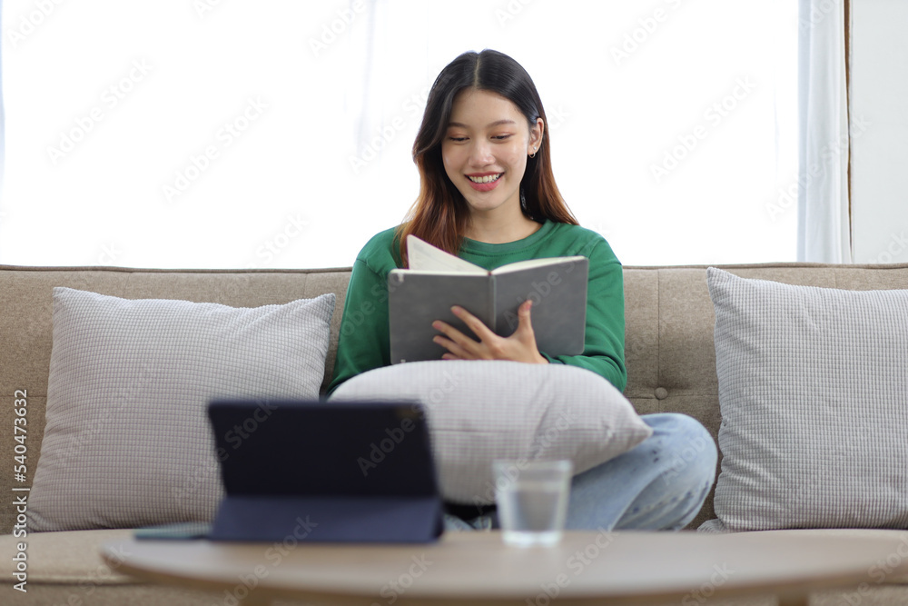 Beautiful asian woman sitting on the sofa reading a book in the house. Beautiful asian woman sitting on the sofa reading a book in the house.
