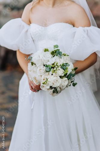 Beautiful wedding bouquet of white roses in the hands of the bride. Close-up photography, portrait.