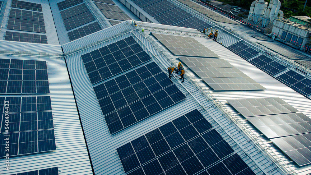 Fly over unidentified Engineering set up a Solar cell on the roof of a large industrial factory. Solar roofs are generating renewable energy for the industry.