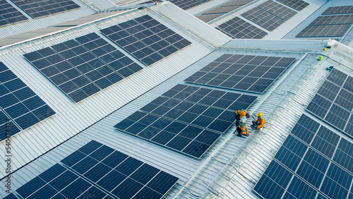 Fly over unidentified Engineering set up a Solar cell on the roof of a large industrial factory. Solar roofs are generating renewable energy for the industry.