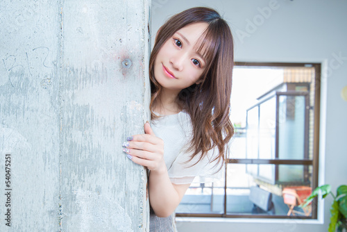 壁から身を乗り出してこちらを見つめるお茶目な日本の若い女性