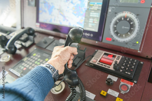 Navigational control panel and VHF radio with hand. Radio communication at sea. Working on the ship's bridge. photo