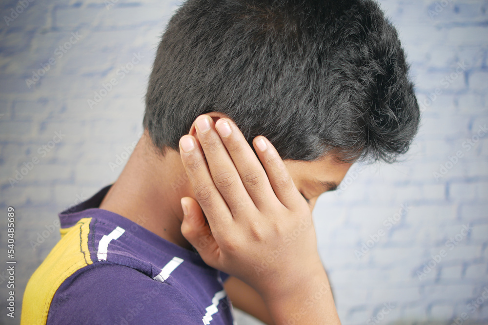 teenage boy having ear pain touching his painful ear ,