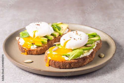 Toast with avocado, soft cream cheese, rye bread and poached Egg. Wholemeal open sandwich for healthy breakfast concept.