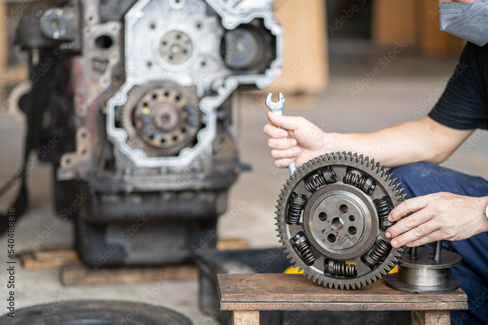 Mechanic man holding front Gear of diesel commonrail engine in heavy machinery workshop Mechanic man holding front Gear of diesel commonrail engine in heavy machinery workshop