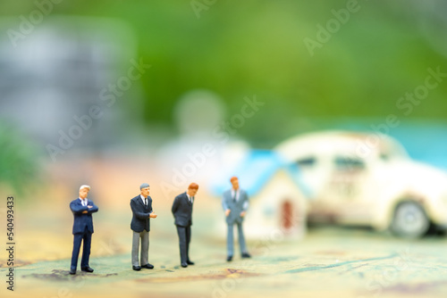 Miniature people: group of businessmen behind the house and the car with copy space for text using as background saving, investment, money, financial, business analytics concept.