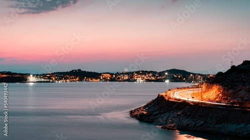 Sunset in Vouliagmeni Athens Greece. Seaside road with trail lights from the moving cars. photo
