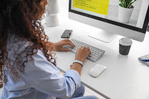 Young web designer working with computer at table in office