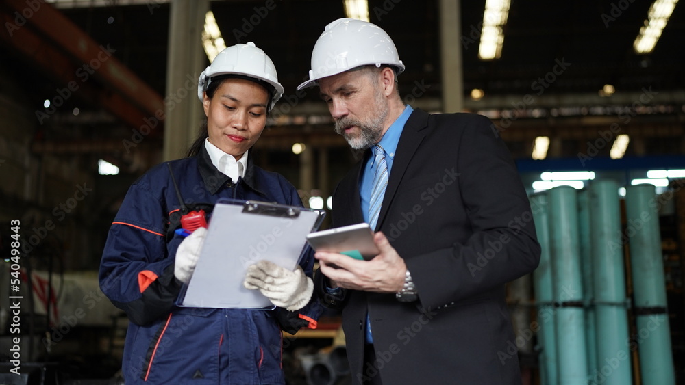 Factory manager or businessman and female engineer in factory. elegant man inspecting factory in industry plant background. Factory manager or businessman and female engineer in factory. elegant man inspecting factory in industry plant background.