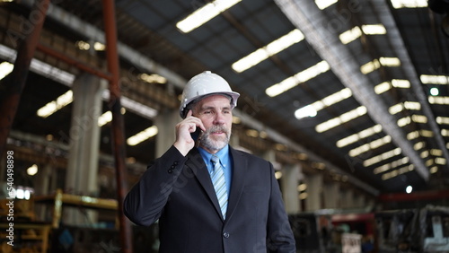 Factory manager or businessman in factory warehouse is talking on mobilephone. Factory indusrty Business.