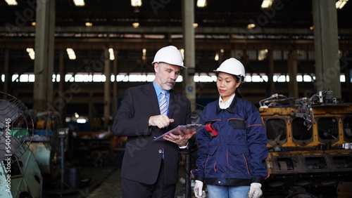 Factory manager or businessman and female engineer in factory. elegant man inspecting factory in industry plant background.