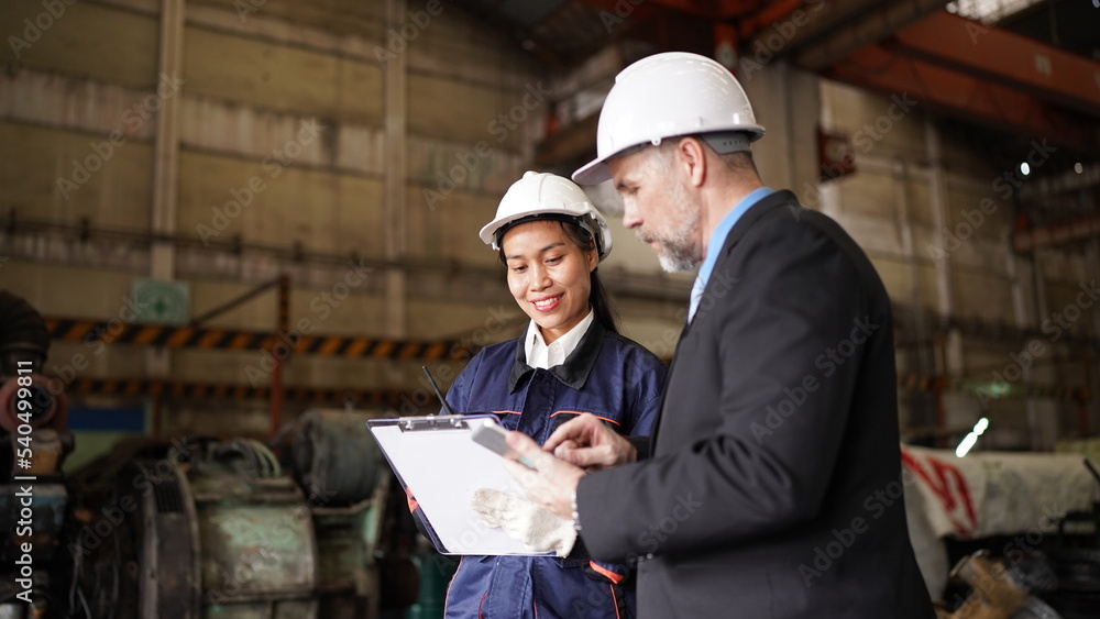 Factory manager or businessman and female engineer in factory. elegant man inspecting factory in industry plant background. Factory manager or businessman and female engineer in factory. elegant man inspecting factory in industry plant background.