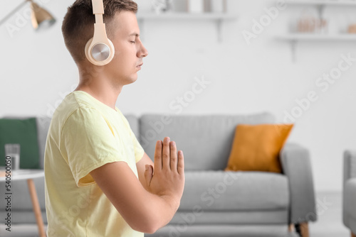 Young man with headphones meditating at home
