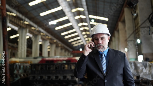 Factory manager or businessman owner in factory warehouse is talking on mobilephone. Business industry background.