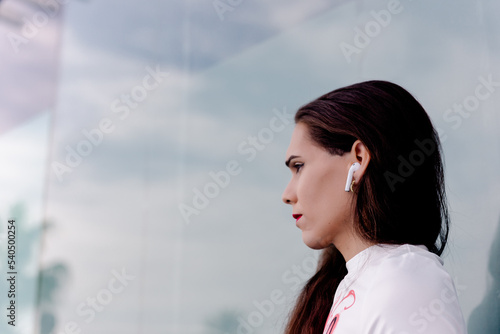 young transgender wearing headphones and talking on his mobile phone