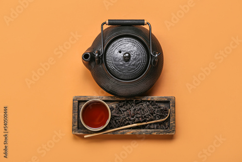 Board with dry puer tea, cup and teapot on orange background photo