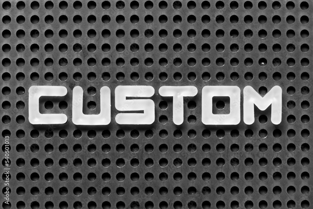 White alphabet letter in word custom on black pegboard background White alphabet letter in word custom on black pegboard background