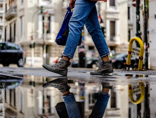Obraz na plátně Walking in a rainy day over puddle with reflection