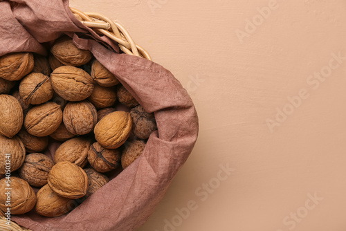 Basket with fresh walnuts on color background