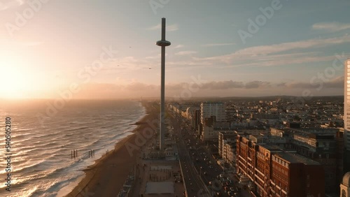 Magical sunset 4k aerial video of British Airways i360 viewing tower pod with tourists in Brighton, UK with sea and Brighton Palace Pier in the background. photo