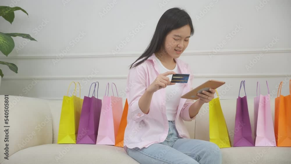 Young asian woman sitting on sofa using digital tablet shopping online with credit card buying to internet, happiness girl paying with transaction financial, purchase and payment, business concept. Young asian woman sitting on sofa using digital tablet shopping online with credit card buying to internet, happiness girl paying with transaction financial, purchase and payment, business concept.