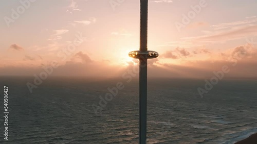 Magical sunset 4k aerial video of British Airways i360 viewing tower pod with tourists in Brighton, UK with sea and Brighton Palace Pier in the background. photo