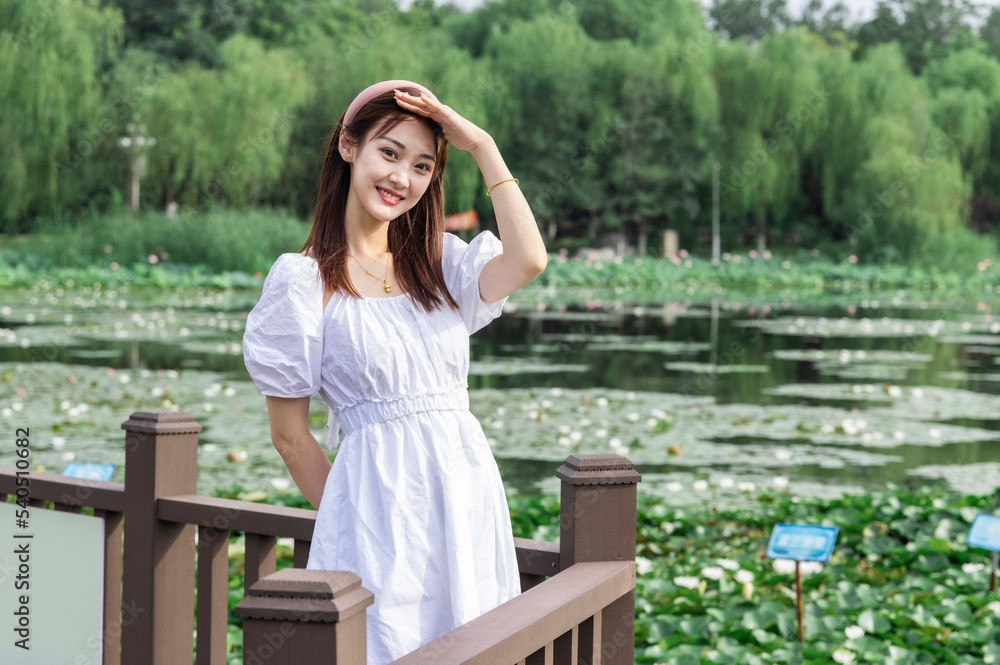 The Asian girl in the white dress by the lake in the park The Asian girl in the white dress by the lake in the park