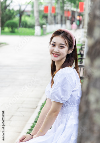 An Asian girl in a white dress playing in the park © 大 李