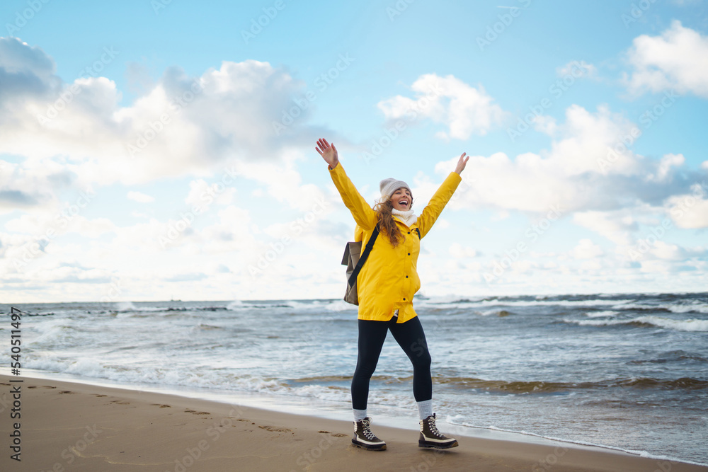 The girl tourist in a yellow jacket posing by the sea. Travelling, lifestyle, adventure.