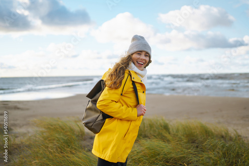 The girl tourist in a yellow jacket posing by the sea. Travelling, lifestyle, adventure.