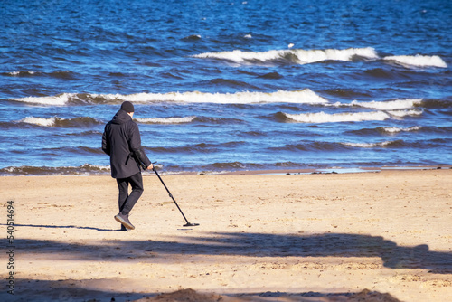 Fototapeta Naklejka Na Ścianę i Meble -  Person with a metal detector walking by the beach finding treasures
