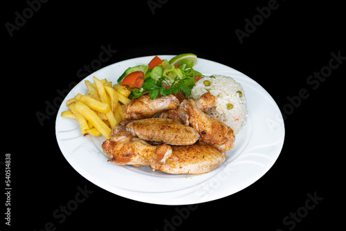Grilled chicken wings with rice, salad and french fries in a white plate