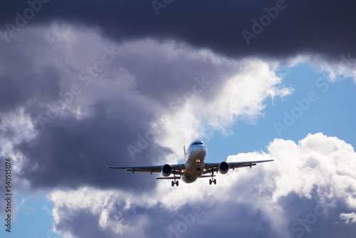 A big white airplane flying in the blue sky with many white and dark blue clouds