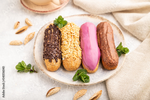 Set of eclair, traditional french dessert and cup of coffee on gray concrete background. side view, close up, selective focus.