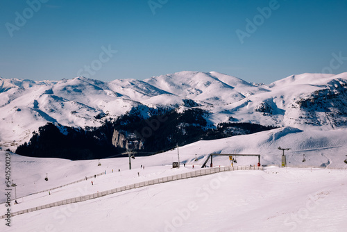 Panoramic view over the ski slope Poiana Brasov ski resort in Transylvania, Pine forest covered in snow on winter season,Mountain landscape in winter with the Bucegi Mountains in the background. photo