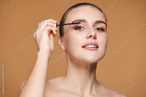woman applying black mascara on long eyelashes with a brush