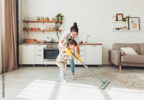 Quadro em tela a little daughter and her mom clean the house, a child washes the kitchen floor, a cute little helper girl cleans the floor with a mop, a happy family cleans the room