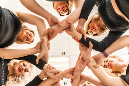 Team of people holding hands. Group of happy young women holding hands. Bottom view  low angle shot of human hands. Friendship and unity concept