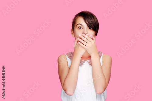 Amazed girl closing her mouth with her hands