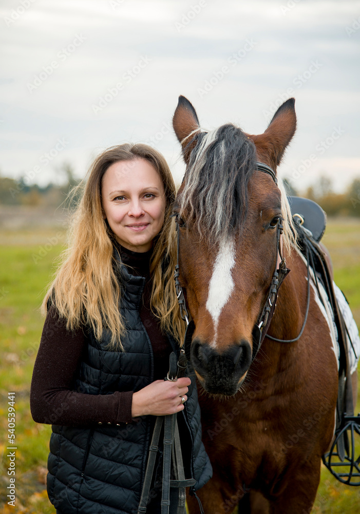 Fototapeta premium portrait of a woman with horse in autumn meadow