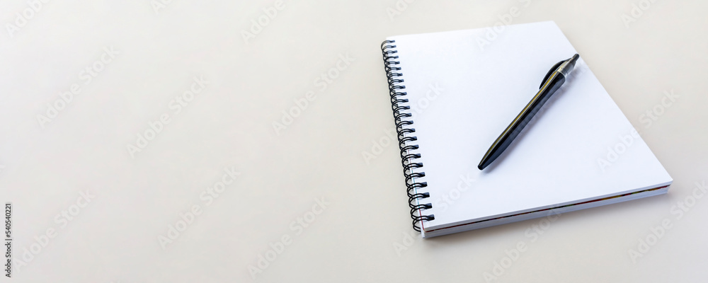 Banner with copy space. Notebook on a spiral on a plain beige background. Blank white sheets in a note. Flat lay, top view. Banner with copy space. Notebook on a spiral on a plain beige background. Blank white sheets in a note. Flat lay, top view.