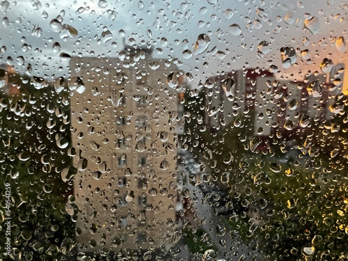 Raindrops through the glass. Drops of rain on a window pane, buildings in background.