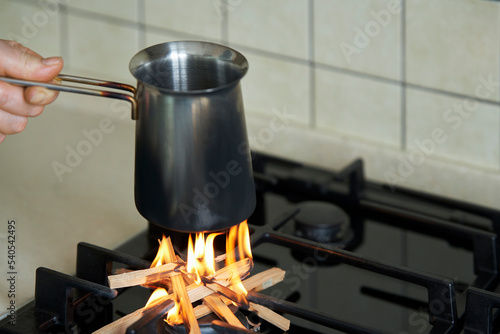 A hand with dishes over the gas stove burner. Firewood is used instead of gas. Selective focus. photo