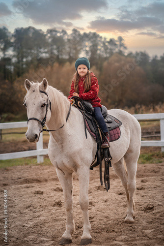 small girl is riding a white horse